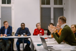 einige Personen sitzen an einem Konferenztisch und diskutieren