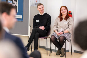 Ein junger Mann und eine junge Frau sitzen auf Sühlen und lächeln